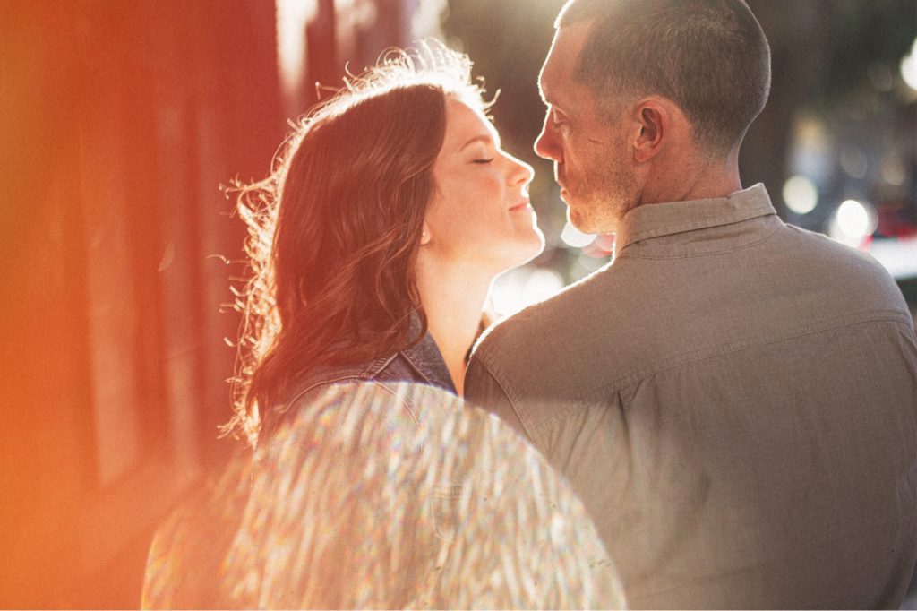 San Luis Obispo Engagement Photography with warm sun-flare of couple nose to nose walking down the street