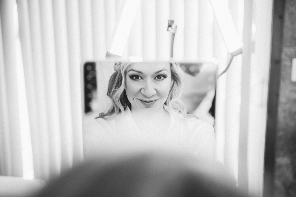 Black and white wedding photo through mirror of a bride getting ready