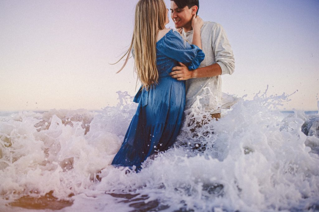 couples romantic engagement session at butterfly beach in the waves of the ocean in Montecito Santa Barbara taken by Montana Dennis