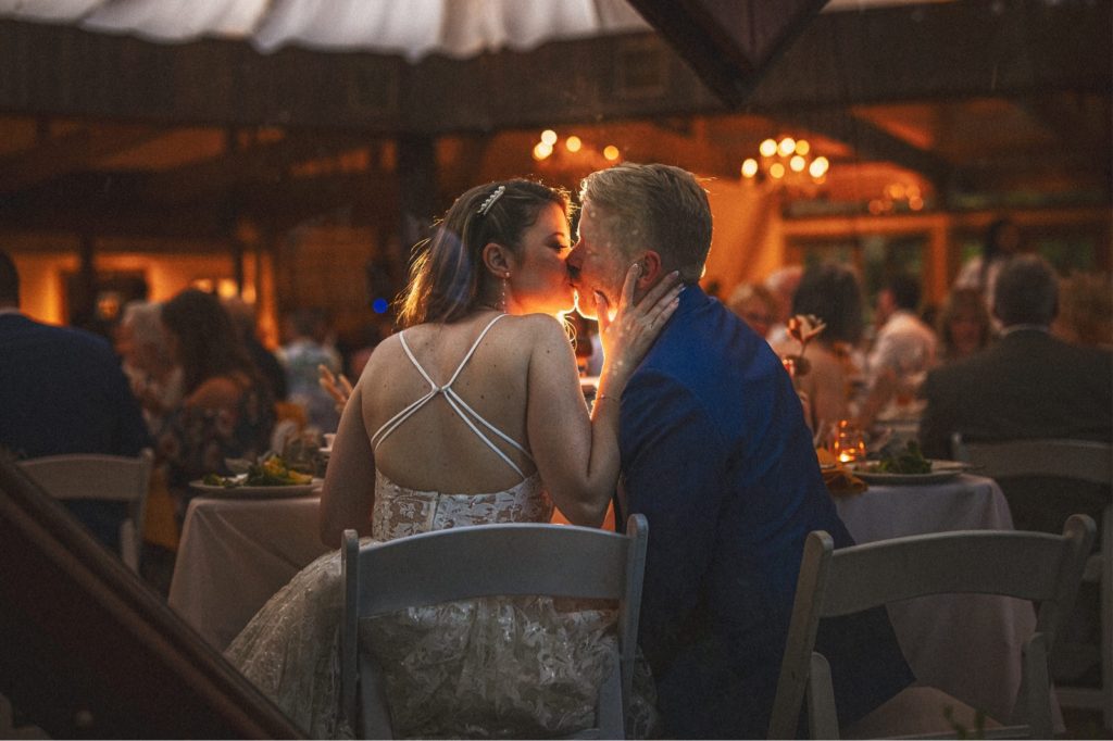 couple kissing at their sweetheart table in the oak room at Calamigos ranch wedding in Malibu 