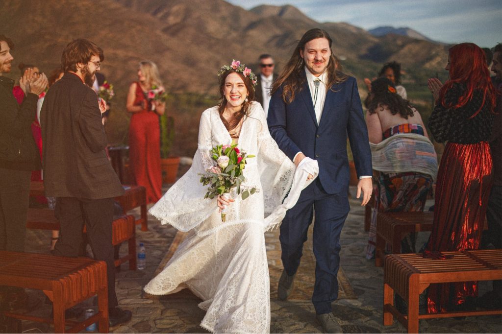Couples exit from their ceremony at the Ojai Labyrinth with the Topatopa mountains in the background with all of their guests