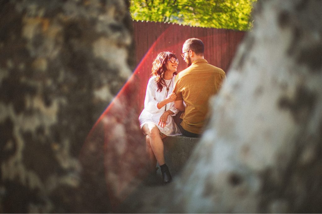 Ojai Engagemnt Session taken in down town Ojai California shot through a tree with the couple look at each other sitting down