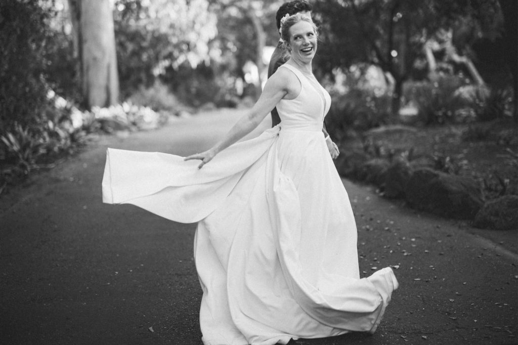 Bride swinging her dress as she walks with her husband at the Rockwood Womans club in Santa Barbara