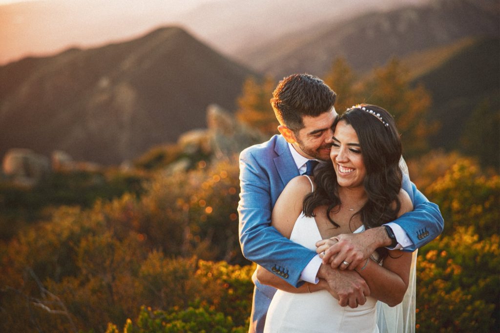 Creative and romantic portrait of couple at their Le Cumbre Peak wedding in Santa Barbara at sunset with the mountains in the back ground