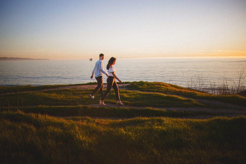 The bride and groom walking along the Bluffs at the Goleta butterfly preserve looking out over the ocean at sunset