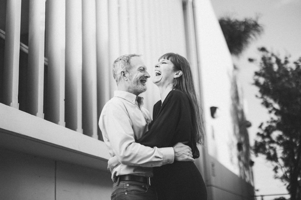 Creative Black and white engagement session photo taken in an alleyway off of Main Street in Ventura for the couple is having a candid moment and laughing together while they hold each other